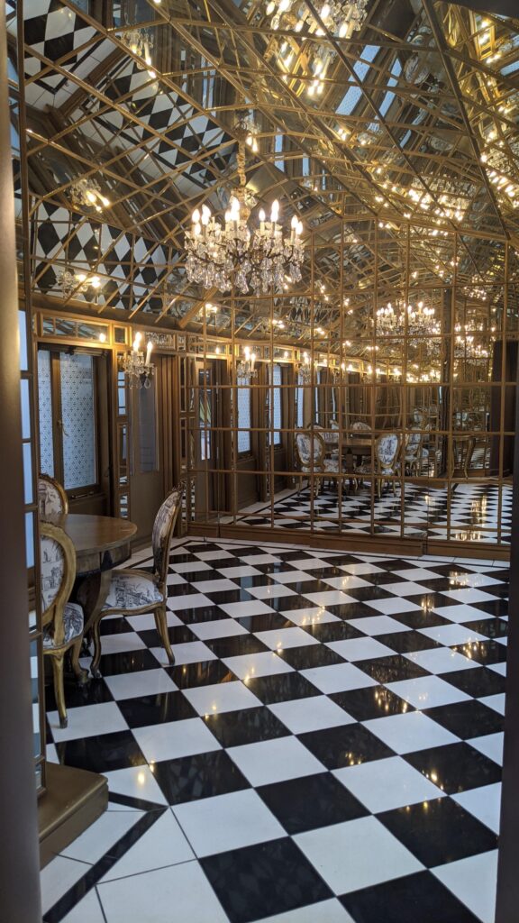 Mirrored dining room with crystal chandelier, gilded latticework and black-and-white chequered marble floor