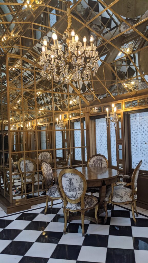 Private dining area with round table, upholstered chairs, crystal chandelier and mirrored walls