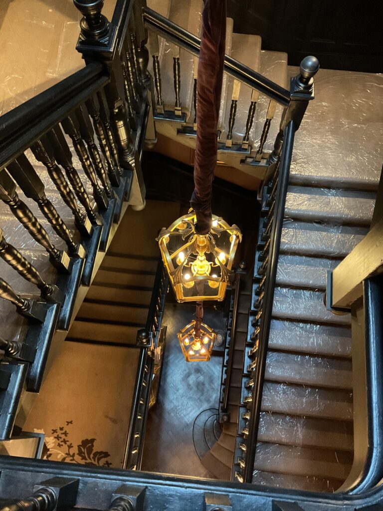 View down a staircase with dark timber balustrade and a lantern pendant