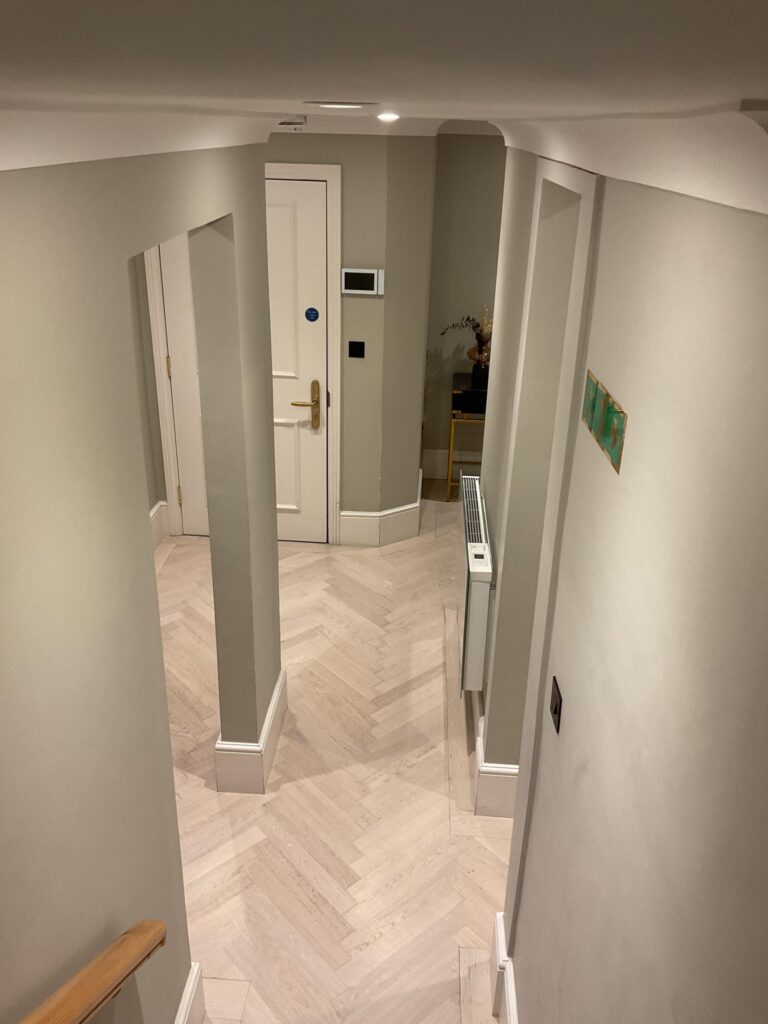 Apartment entrance hall with pale herringbone timber floor and panelled doors