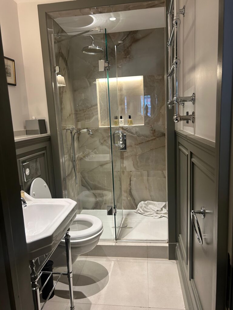 Shower room with marble-clad walk-in shower, glass screen and basin