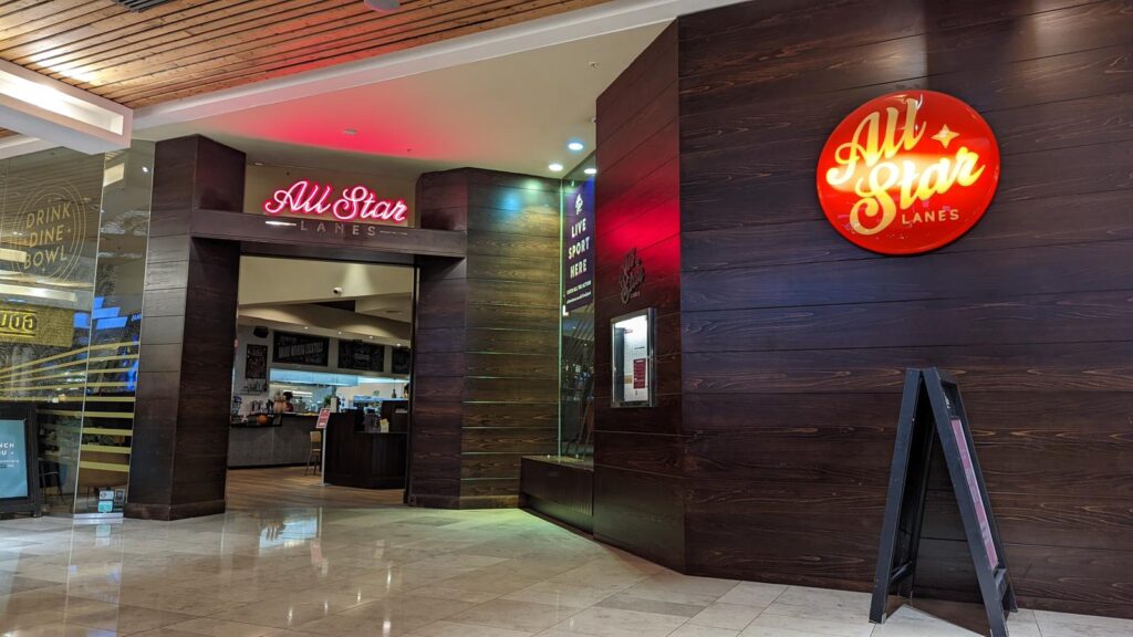 Entrance to All Star Lanes with illuminated red signage and dark timber cladding