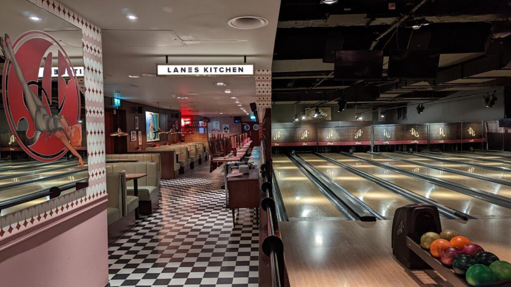 Bowling lanes with ball returns beside a black-and-white chequered walkway