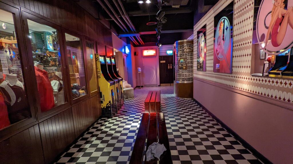 Corridor with chequered floor, arcade machines and pink patterned walls
