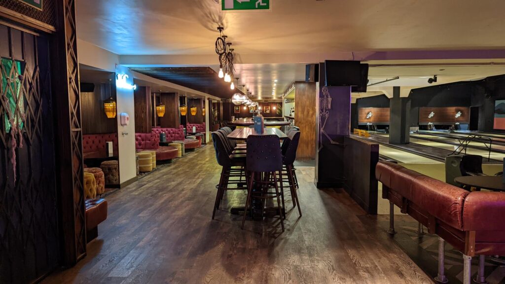 Bar lounge with high tables, red upholstered seating and pendant lights