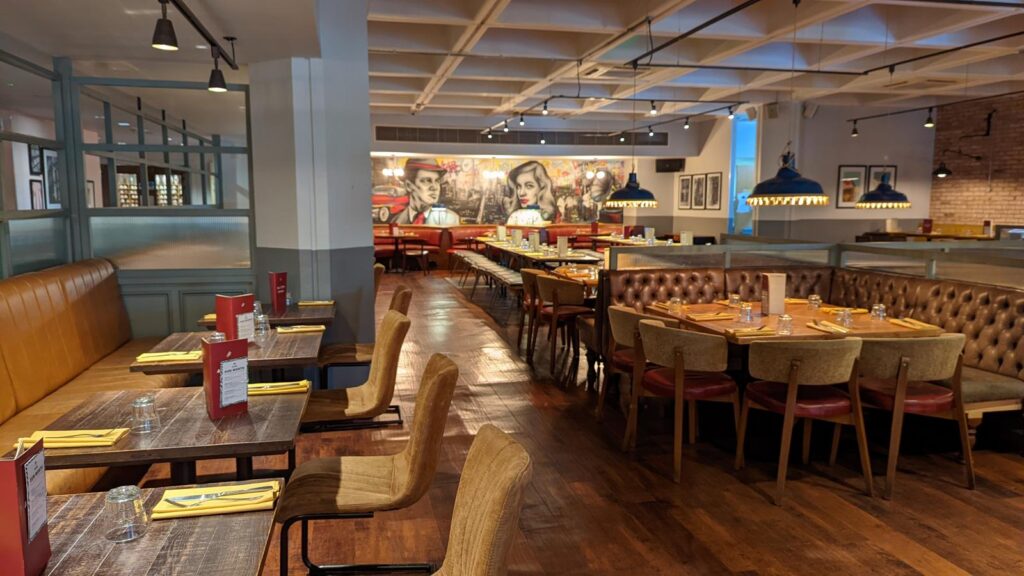 Restaurant dining area with timber tables, leather booths and a mural
