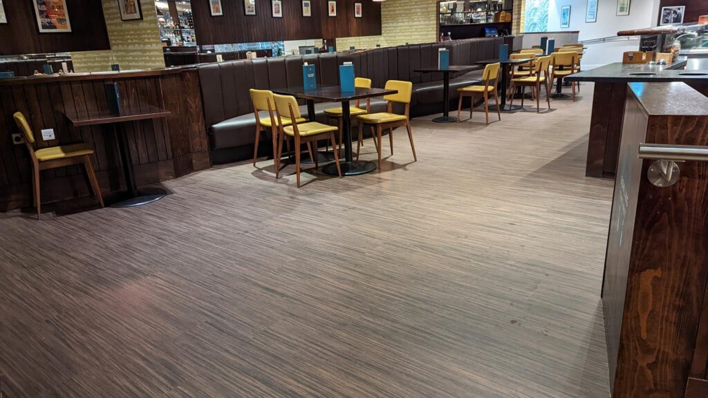 Dining area with yellow chairs, timber tables and wood-effect flooring