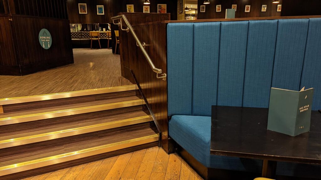 Raised seating area with blue upholstered booth and timber steps with brass nosings