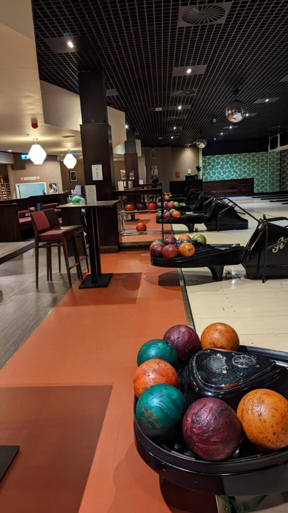 Bowling ball rack beside high tables on an orange floor
