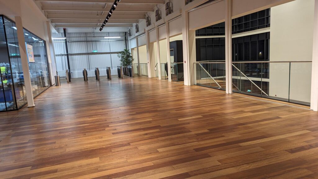 Long hall with timber floor, glazed partitions and full-height windows