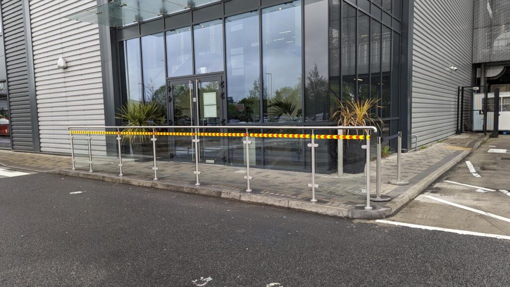 Glazed building entrance with planters and a glass-and-steel balustrade